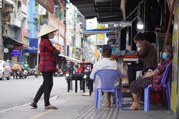 ベトナム・ホーチミン市の歓楽街の一つであるブイビエン通りでは、閉店が続くバーの軒先にミシンを置き、洋服の修理で日銭を稼ぐ人の姿も（同市１区）