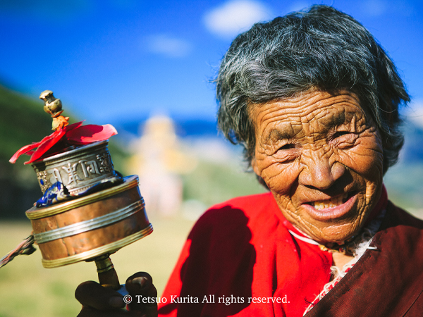 功徳を積むためにマニ車と呼ばれる仏具を回すチベット族の女性＝中国・青海省撮影