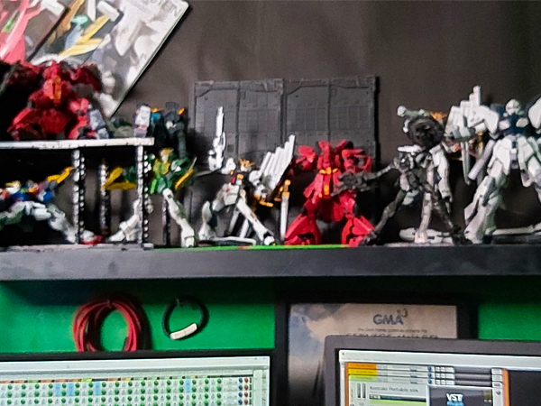 作業スペースに飾られた「機動戦士ガンダム」などのプラモデル。仕事が終わった後に組み立てるのが日課(同)