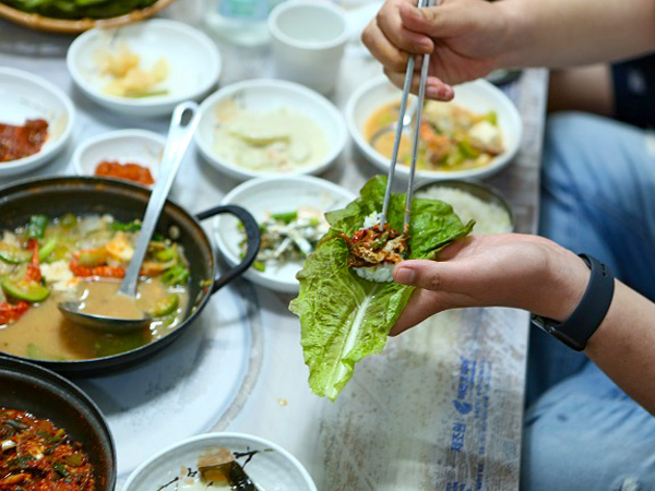 カタクチイワシをサンチュに巻いて食べるツアー参加者（韓国海洋水産省提供）