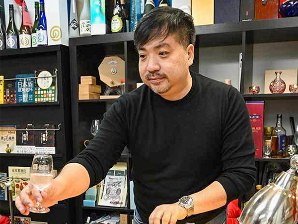 香港に到着した「ねっか」の日本酒をテイスティングする楊さん（ＮＮＡ撮影）