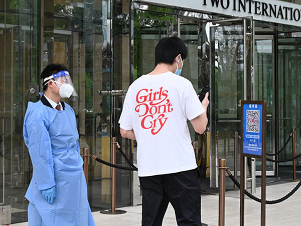 オフィス街、陸家嘴のビル前の出勤風景。ビルに入る際は出入り口に設置された「場所コード」という2次元コードをスマートフォンで読み取る必要がある=6月1日、中国・上海市