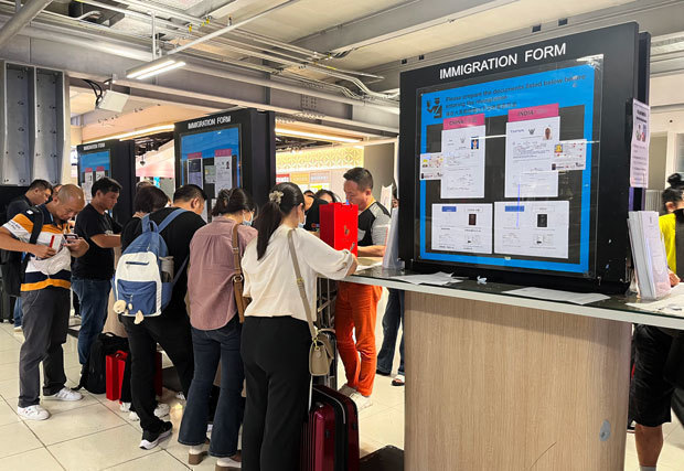 タイの玄関口、スワンナプーム国際空港で到着ビザの申請書類を書く中国人旅行者ら。25日から、中国人は手続きなしで入国が可能となる＝18日、タイ・バンコク近郊（ＮＮＡ撮影）