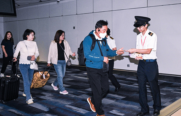 香港国際空港では食品環境衛生署職員（右）が旅行客にトコジラミに関するリーフレットを配布＝８日（香港政府提供）