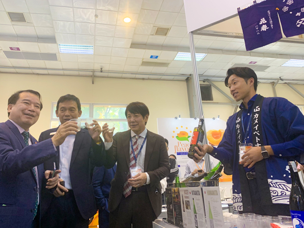 ジェトロは食品展示会で「ジャパン・パビリオン」を開設した。写真はカメイ・ベトナムのブースで試飲するベトナム国家観光総局（ＶＮＡＴ）のハー・バン・シエウ次長（左）など＝21日、ハノイ