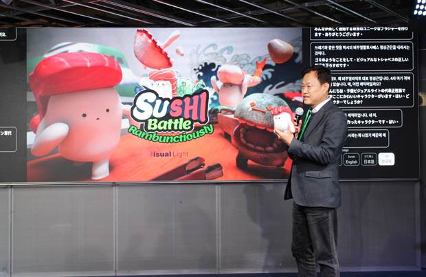 すしバトルのキャラクター人形を持って、プレゼンするビジュアルライトのチョンＣＥＯ＝11月30日、福岡市（ＮＮＡ撮影）