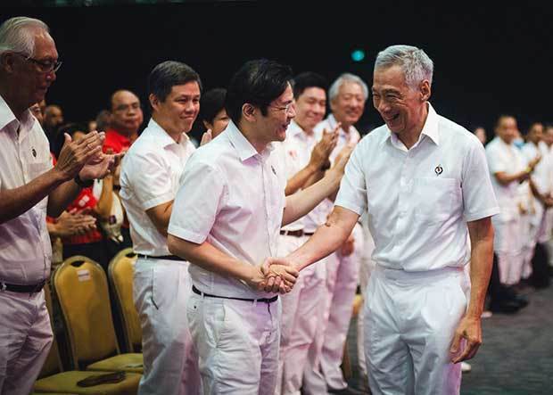 与党・人民行動党の党大会で、ローレンス・ウォン副首相兼財務相（中央左）と握手を交わすリー・シェンロン首相（人民行動党提供）