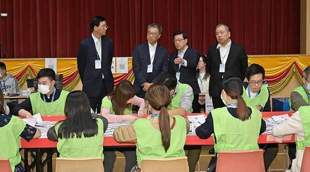 区議会議員選挙の開票作業を見守る李家超行政長官（後列右２）ら＝11日（香港政府提供）