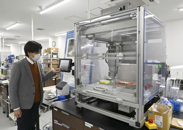 培養肉の自動生産装置。左は松崎典弥大阪大教授＝３月、大阪府吹田市の大阪大（共同）