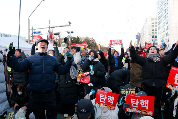 弾劾案が可決され国会議事堂前で喜ぶ人たち＝14日、ソウル（ＮＮＡ撮影）
