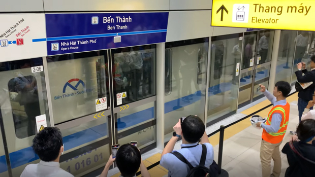 開業式典でベンタイン駅を出発する車両を見送る招待客ら＝22日、ホーチミン市