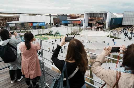 大阪・関西万博が開幕し、大屋根リングから写真を撮る来場者＝13日午前、大阪市此花区の夢洲（共同）