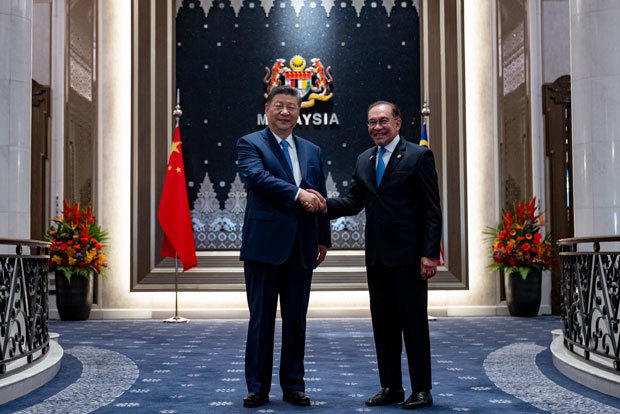 握手する習国家主席（左）とアンワル首相＝16日、プトラジャヤ（アンワル氏の公式フェイスブックより） 
