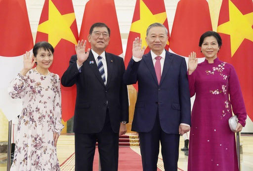 記念撮影に応じるベトナムのトー・ラム共産党書記長（中央右）と石破首相（同左）。左は妻の佳子さん＝27日、ハノイ（共同）