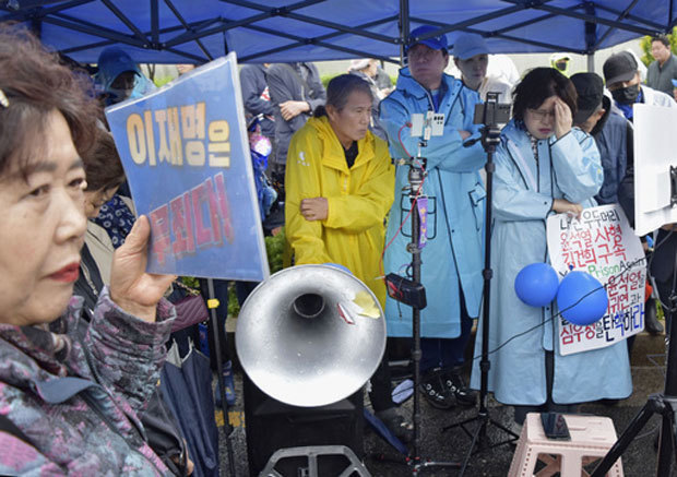 １日、ソウルの韓国最高裁前で、最大野党「共に民主党」の李在明前代表に対する判決を険しい表情で聞く支持者ら（共同）