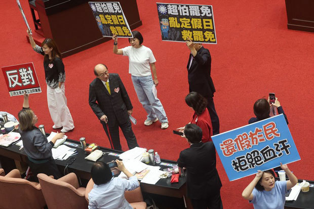 公定休日を増やす条例案に対し立法院の議場で賛成と賛成のプラカードを掲げてそれぞれの正当性をアピールする与野党の議員（中央通信社）