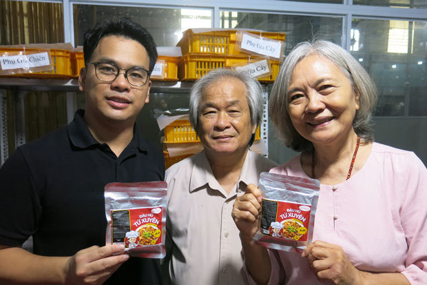 「豆腐入り」インスタント麻婆豆腐を手に取るカオ・ミン・ケン副社長（左）ら。中央はカオ・ミン・タイ社長＝９日、アンザン省