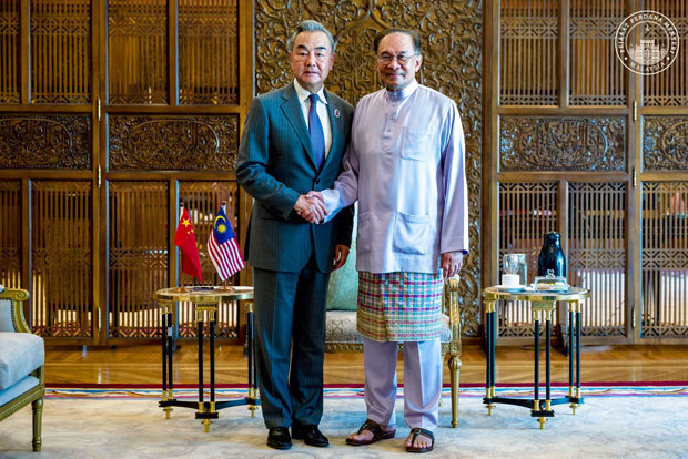 握手する王外相（左）とアンワル首相＝11日、プトラジャヤ（アンワル氏の公式フェイスブックより）