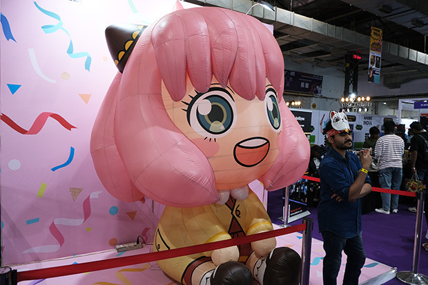 会場に設置された人気アニメ「ＳＰＹ×ＦＡＭＩＬＹ（スパイファミリー）」のキャラクター人形と写真を撮る来場者＝22日、西部ムンバイ（ＮＮＡ撮影）