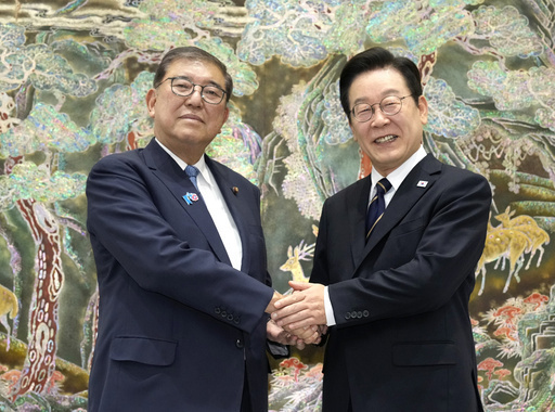 首脳会談の会場に到着し、韓国の李在明大統領（右）の出迎えを受け握手する石破首相＝９月30日、釜山（共同）