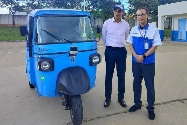 オメガ・セイキ・モビリティーの新しい電動三輪車の前で写真撮影に応じる創業者兼会長のウダイ・ナラン氏（左）とエクセディ・クラッチの草水氏＝９月、インド南部ベンガルール近郊コラー地区ナラサプラにあるエクセディ・クラッチの工場（ＮＮＡ撮影）