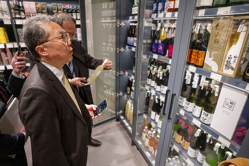 ウクライナ・キーウのスーパーに陳列された日本酒を見る日本の代表団のメンバー＝28日（共同）