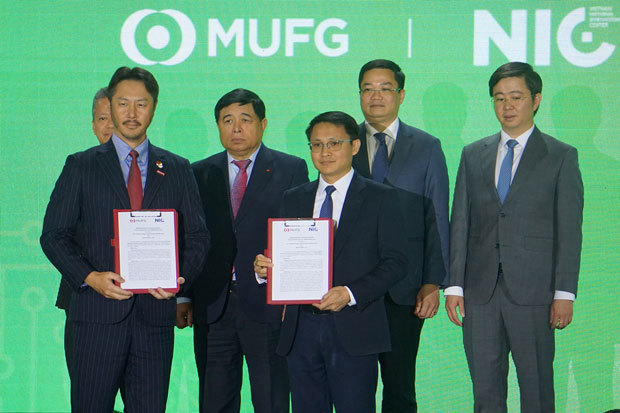 グエン・チー・ズン副首相（後列左から２人目）の立ち合いで、三菱ＵＦＪ銀とＮＩＣは覚書を結んだ。前列左が鈴木副支店長。右がＮＩＣの代表＝７日、ハノイ市