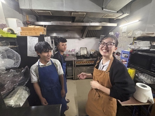 おにぎり専門店のキッチンでスタッフと談笑する古田里奈さん（右）＝11月、インド・ニューデリー（共同）