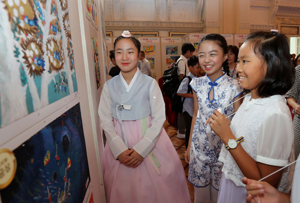日中韓の児童友好絵画展が開幕し、３カ国の児童らが一緒に作品を見て回った＝７月28日、上海市（新華社）