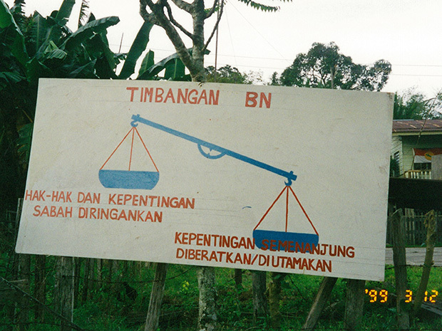1999年のサバ州議会選挙のときに立てられた看板。左側（サバの権利）が右側（マレー半島部の権利）より軽くて天秤（国民戦線のシンボル）が傾いている（筆者撮影）