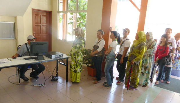 投票所入口に並んで有権者名簿の確認を待つ有権者たち。地方のマレー人と先住諸族の票が選挙結果を大きく左右する（筆者撮影）