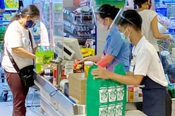 商業施設内のスーパーマーケットでフェースシールドをしてやりとりする客と店員ら＝８月上旬、マニラ首都圏マカティ市（ＮＮＡ撮影）