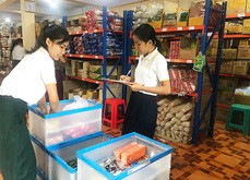 配送拠点で顧客の注文に応じた商品を折りたたみ式の箱に詰めるリンクルージョンのスタッフ＝８月26日、ヤンゴン管区カウム郡区（ＮＮＡ）