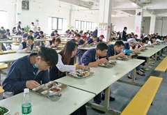 日系電子部品メーカーの食堂では、対面しないよう従業員が一方向を向いて食事をとっている＝10月30日、広東省仏山市