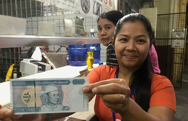 アウン・サン将軍の肖像画が入った紙幣を手に、満足げな笑顔の女性＝１月８日、ヤンゴン（ＮＮＡ）
