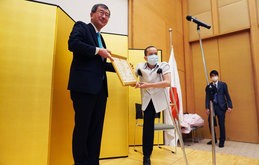 渡邊信裕在ホーチミン総領事から花束を受けるグエン・ドクさん（右）