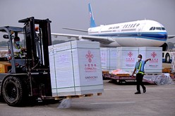 中国から空輸された新型コロナのワクチンを運搬するミャンマーの空港スタッフ＝2021年12月、ヤンゴン（新華社）