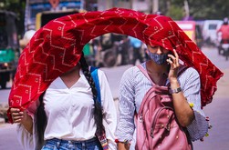 厳しい暑さの中、スカーフで日差しを遮る通行人＝４月28日、インド北部グルガオン（ＰＴＩ）