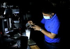 ミャンマー・ヤンゴンで停電中、わずかな明かりを頼りに営業するカフェの店員＝16日（共同）