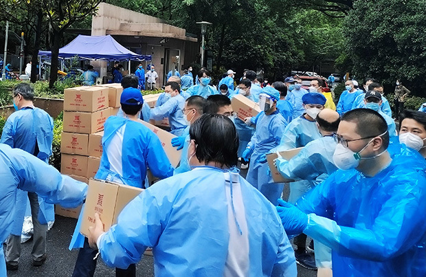 ロックダウン期間は小区の一部住民がボランティアに名乗り出て、小区運営の労働力を担った。５月末のこの日、政府支給品の荷下ろしのため大勢のボランティアが汗をかいた＝上海市