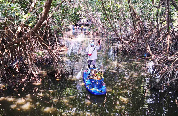 タイの川でスターボード製のスタンドアップパドルボードをこぎながら清掃活動をする人（同社提供）