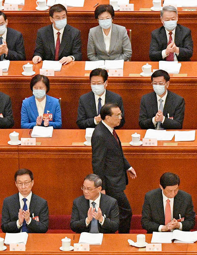 中国全人代で政府活動報告を終え席に戻る李克強首相。前列中央は拍手する李強氏＝５日、北京の人民大会堂（共同）