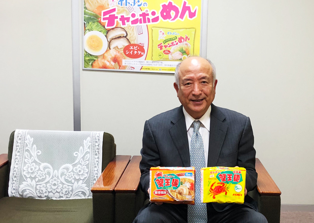 イトメンの伊藤社長。左手に持った黄色いパッケージがオリジナルの蟹王麺、右手のオレンジ色は豚骨風味（イトメン提供）