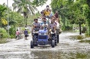 大規模洪水が続くインド北東部アッサム州の村で、冠水した道をトラクターで通勤する住人ら＝23日（ＰＴＩ）